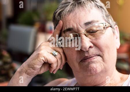 Porträt einer älteren Frau mit Brille und geschlossenen Augen denken Stockfoto