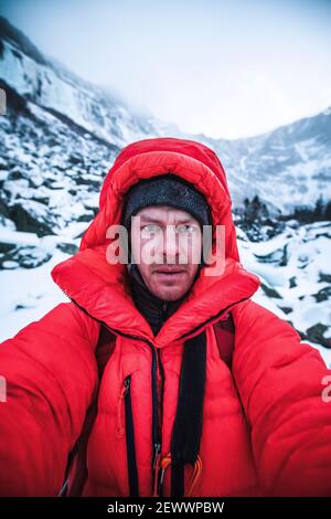 Mann in rot geschwollenen Jacke nimmt Selfie in sehr kalten Bedingungen. Stockfoto