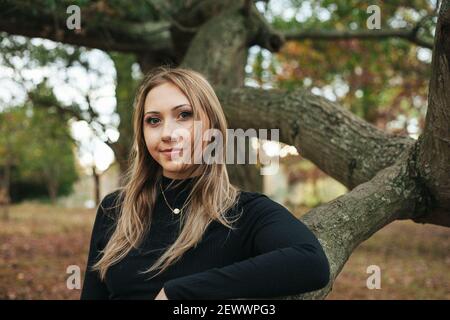 Eine junge Frau steht in einer großen Eiche Ein Park in Virginia Stockfoto