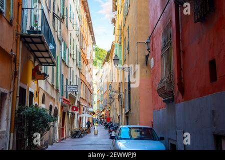 Eine der vielen engen Gassen mit hohen Mauern von Wohnungen und Geschäften durch die Altstadt Vieux Nizza, Frankreich, an der französischen Riviera. Stockfoto