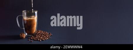 Banner mit Milch Gießen in schwarzen Kaffee in Glas Tasse auf dunkelblauem Hintergrund mit Bohnen und Schokolade Trüffel. Kaffee Liebe Konzept. Vorderansicht Stockfoto