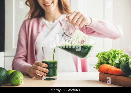 Nahaufnahme Foto von einer Ingwer Frau Putting etwas frisch Grüner Saft in einem Glas Stockfoto