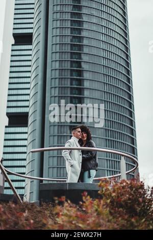 Eine vertikale Aufnahme von einem schönen Paar mit einem Hohes Gebäude im Hintergrund Stockfoto