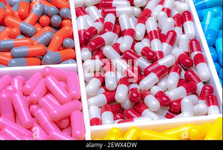 Rot-weiße, orange-graue, rosa, blau und gelbe Kapseln in Kunststoff-Tablett. Antibiotika-Kapsel Pillen. Pharmaindustrie. Droge der Wahl. Stockfoto