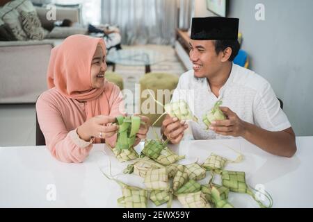 Schöne muslimische paar asiatische Herstellung ketupat Reiskuchen zu Hause Mit Palmblatt Stockfoto