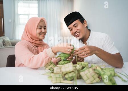 Schöne muslimische paar asiatische Herstellung ketupat Reiskuchen zu Hause Mit Palmblatt Stockfoto
