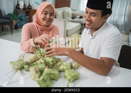 Schöne muslimische paar asiatische Herstellung ketupat Reiskuchen zu Hause Mit Palmblatt Stockfoto