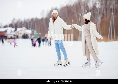 Womans Freunde lernen im Winter auf der Eisbahn Schlittschuh laufen. Konzept Hilfe, Training, gesunde Erholung, Lebensstil. Stockfoto