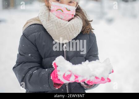 Das Bild zeigt ein Porträt eines kleinen kaukasischen Mädchens Mit Schnee auf ihre Handschuhe während einer schweren aufgenommen Schneefall Stockfoto