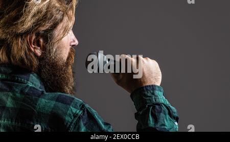 Mann hält ein Mikrofon und singt. Bärtiger Mann, der mit Mikrofon singt. Männlicher Gesang mit Mikrofonen. Bärtiger Mann in Karaoke singt ein Lied in ein Stockfoto