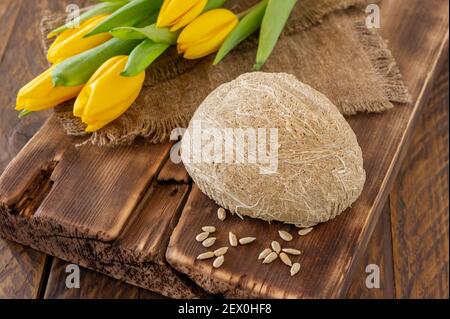 Seitenansicht von Halva, orientalisches süßes Dessert aus Erdnussölsamen, zu einer Paste gemahlen und mit Zuckersirup gemischt, serviert auf Holzschreibtisch mit Blumen. Stockfoto