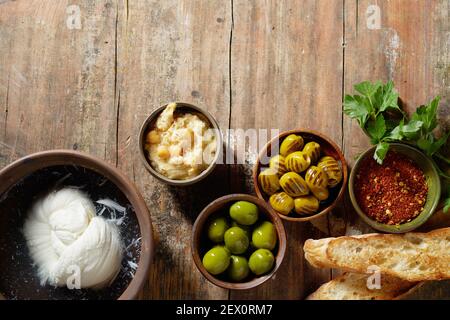 Draufsicht auf eingelegte Oliven mit Gewürzen und Hummus platziert In der Nähe Baguette Toasts und Mozzarella Käse auf Holztisch Stockfoto