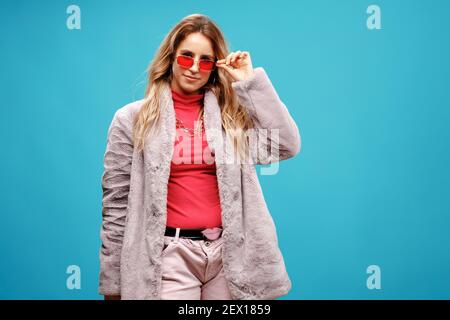 Porträt einer jungen modischen Frau in Kunstfellmantel Vor blauem Hintergrund Stockfoto