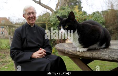 Der Dekan von Canterbury, Reverend Dr. Robert Willis mit Domkatze Lilly, einer von drei schelmischen Katzen, die auf dem 1.400 Jahre alten Sitz der Anbetung in Kent leben, der seine Videogebete ständig stört und zu einem Social-Media-Hit geworden ist. Bilddatum: Dienstag, 2. März 2021. Stockfoto