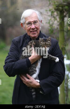 Der Dekan von Canterbury, Reverend Dr. Robert Willis mit Domkatze Tiger, einer von drei schelmischen Katzen, die auf dem 1.400 Jahre alten Sitz der Anbetung in Kent leben, der seine Videogebete ständig stört und zu einem Social-Media-Hit geworden ist. Bilddatum: Dienstag, 2. März 2021. Stockfoto