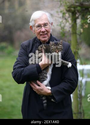 Der Dekan von Canterbury, Reverend Dr. Robert Willis mit Domkatze Tiger, einer von drei schelmischen Katzen, die auf dem 1.400 Jahre alten Sitz der Anbetung in Kent leben, der seine Videogebete ständig stört und zu einem Social-Media-Hit geworden ist. Bilddatum: Dienstag, 2. März 2021. Stockfoto