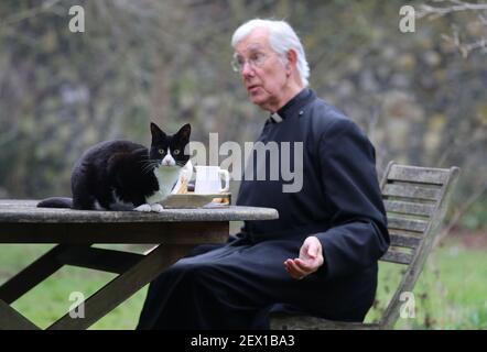 Der Dekan von Canterbury, Reverend Dr. Robert Willis mit Domkatze Lilly, einer von drei schelmischen Katzen, die auf dem 1.400 Jahre alten Sitz der Anbetung in Kent leben, der seine Videogebete ständig stört und zu einem Social-Media-Hit geworden ist. Bilddatum: Dienstag, 2. März 2021. Stockfoto