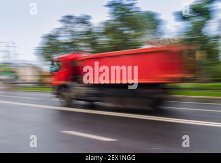 Dump Truck fährt schnell auf der Stadtstraße Stockfoto