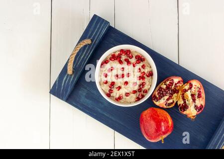 Gesundes Frühstück Haferflocken mit Granatapfel, Äpfel, Samen und Nüsse, Overhead Schuss auf weißen Holztisch. Stockfoto