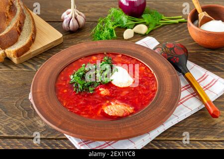 Borsch: Traditionelle ukrainische und russische Rote Beete-Suppe auf dunklem Holzgrund. Serviert mit Roggenbrot, Knoblauch und Salz. Stockfoto