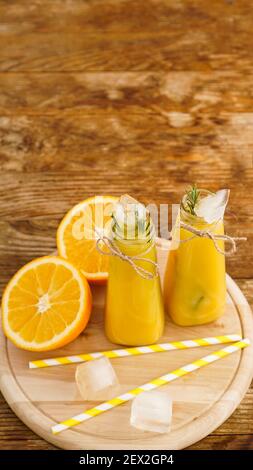 Orangensaft auf einem Holztablett in Scheiben geschnittene Orangen- und Eiswürfel. Snack im Resort, Kühle an einem heißen Sommertag. Vertikales Foto Stockfoto