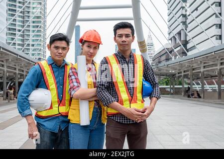 Team von multi ethnischen Ingenieur Vertrauen stehend und hält Blaupause, Sicherheitshelm auf der Baustelle in der Stadt Stockfoto