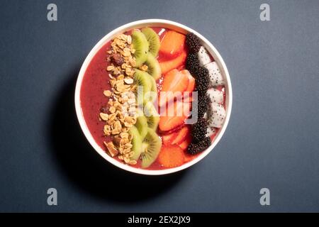 SCHWARZE TRAUBEN, ERDBEERE UND FEIGEN SMOOTHIE MIT DRACHENFRUCHT, KIWI, ERDBEERE, MAULBEERE UND CRANBERRY-MANDEL-MÜSLI GEKRÖNT Stockfoto