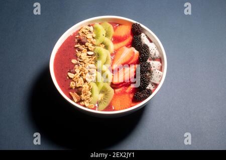 SCHWARZE TRAUBEN, ERDBEERE UND FEIGEN SMOOTHIE MIT DRACHENFRUCHT, KIWI, ERDBEERE, MAULBEERE UND CRANBERRY-MANDEL-MÜSLI GEKRÖNT Stockfoto