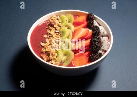 SCHWARZE TRAUBEN, ERDBEERE UND FEIGEN SMOOTHIE MIT DRACHENFRUCHT, KIWI, ERDBEERE, MAULBEERE UND CRANBERRY-MANDEL-MÜSLI GEKRÖNT Stockfoto