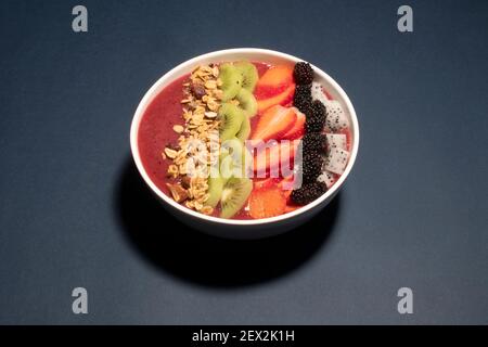 SCHWARZE TRAUBEN, ERDBEERE UND FEIGEN SMOOTHIE MIT DRACHENFRUCHT, KIWI, ERDBEERE, MAULBEERE UND CRANBERRY-MANDEL-MÜSLI GEKRÖNT Stockfoto