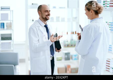 Leitende Apothekerin diskutiert etwas mit ihrem Kollegen. Stockfoto