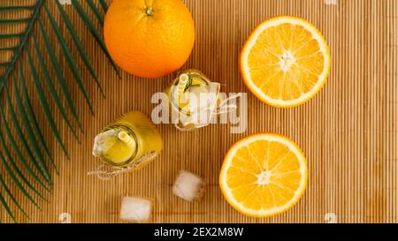 Orangensaftflaschen und Papierhalme. Eisiger Drink an einem sonnigen Tag. Eisstücke in einer Flasche und auf einer Bambusserviette. Draufsicht Stockfoto
