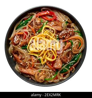 Japchae in schwarzer Schale isoliert auf weiß. Koreanische Küche Glas Chapchae Nudeln Gericht mit Gemüse und Fleisch. Traditionelle asiatische Küche. Authentische Mahlzeit. Stockfoto