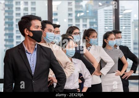 Reihe der multiethnischen Gruppe trägt Gesichtsmaske gestikulierenden Arm akimbo in neuen normalen Büro während Pandemie des Coronavirus, covid 19 Stockfoto