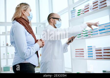 Apotheker in Schutzmasken mit einer digitalen Tablette . Stockfoto