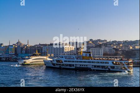 Istanbul, Türkei - 2. Februar 2021 - wunderschöne Sonnenuntergangsansicht der Docks von Eminönü mit Fähren und der Hagia Sophia große Moschee auf dem Hügel Stockfoto