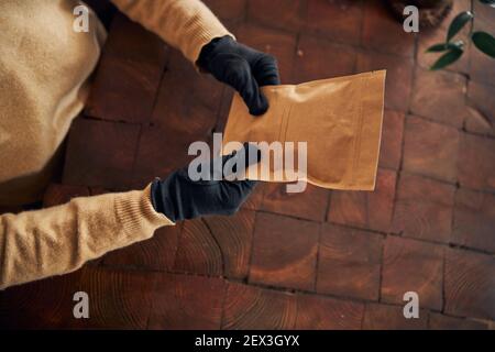 Männliche Hände in Handschuhen, die Kraftpapier-Beutel halten Stockfoto