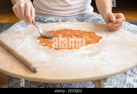 Hausgemachte Lahmacun Vorbereitung von Anfang bis Ende. Die Füllung wird in den Teig gelegt, der auf dem Bodentisch geöffnet ist. Stockfoto