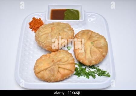 Kachori mit trockenem Knoblauch Chutney garniert mit Korianderblättern Kachori ist ein würziger Snack aus Indien, der auch als Kachauri und Kachodi geschrieben wird. Weiße Rückseite Stockfoto