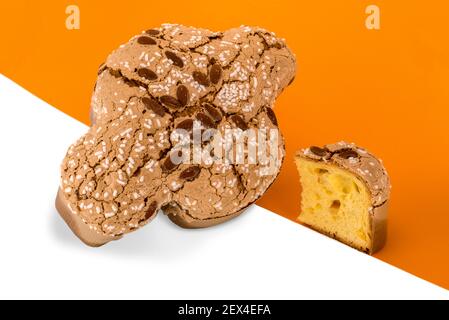 Colomba Pasquale, italienische Ostertaube mit glasierten Zucker und Mandeln. Kuchen und Scheiben auf weißem orangefarbenem Hintergrund Stockfoto
