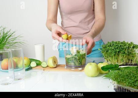 Schritt-für-Schritt-Rezept für die Herstellung von Smoothies aus Mikro-grünen Äpfeln Gurke und Spinat. Frau Hände schneiden Gemüse und legen Sie sie in Mixer zum Schlagschlagen Stockfoto