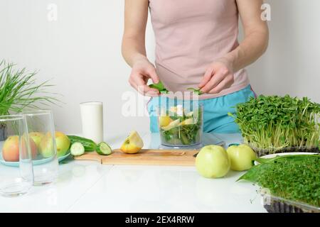 Schritt-für-Schritt-Rezept für die Herstellung von Smoothies aus Mikro-grünen Äpfeln Gurke und Spinat. Frau Hände schneiden Gemüse und legen Sie sie in Mixer zum Schlagschlagen Stockfoto