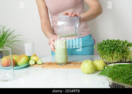 Schritt-für-Schritt-Rezept für die Herstellung von Smoothies aus Mikro-grünen Äpfeln Gurke und Spinat. Frau Hände schneiden Gemüse und legen Sie sie in Mixer zum Schlagschlagen Stockfoto