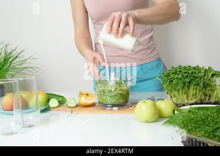 Schritt-für-Schritt-Rezept für die Herstellung von Smoothies aus Mikro-grünen Äpfeln Gurke und Spinat. Frau Hände schneiden Gemüse und legen Sie sie in Mixer zum Schlagschlagen Stockfoto