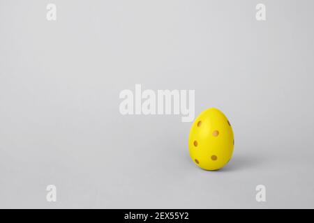 Trendiges buntes Osterei in Gelb auf grauem Hintergrund mit Kopierfläche. Minimalistisches Grußkartenkonzept. Stockfoto