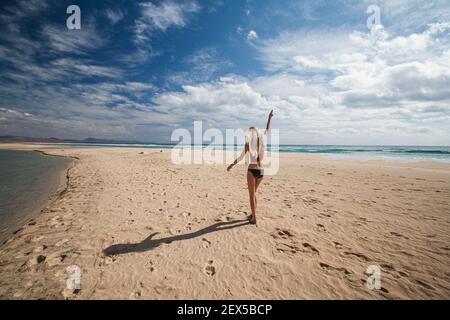 Glückliche Frau geht über Sandstrand in der Nähe des Ozeans Stockfoto