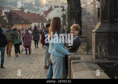 Prag, Tschechische Republik. 03-02-2021. Junges Paar im Winter auf der Karlsbrücke im Stadtzentrum von Prag reden, lächeln und Spaß haben Stockfoto