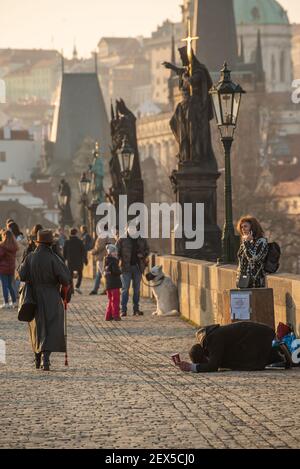 Prag, Tschechische Republik. 03-02-2021. Bettler, der im Winter auf der Karlsbrücke im Stadtzentrum von Prag um Geld bat. Stockfoto
