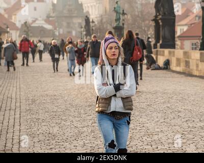 Prag, Tschechische Republik. 03-02-2021. Junge Frau, die im Winter auf der Karlsbrücke im Stadtzentrum von Prag mit einem wunderschönen Sonnenuntergang spazierengeht. Stockfoto