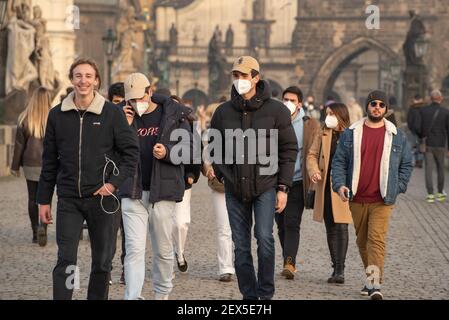 Prag, Tschechische Republik. 03-02-2021. Junge Männer mit Maske gehen im Winter mit einem schönen Su auf der Karlsbrücke im Stadtzentrum von Prag Stockfoto